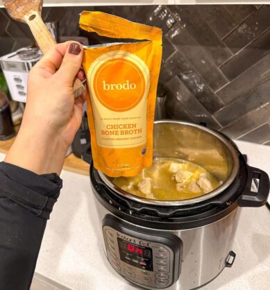 Influencer holding up Brodo bone broth above an Instant Pot in the kitchen