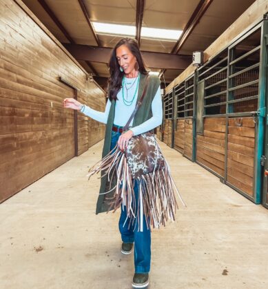 Influencer poses with Jill's Homestead fringe bag with cow print