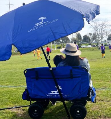 Mom influencer sits with her child on the converted Lounge Wagon seat during a kids soccer game