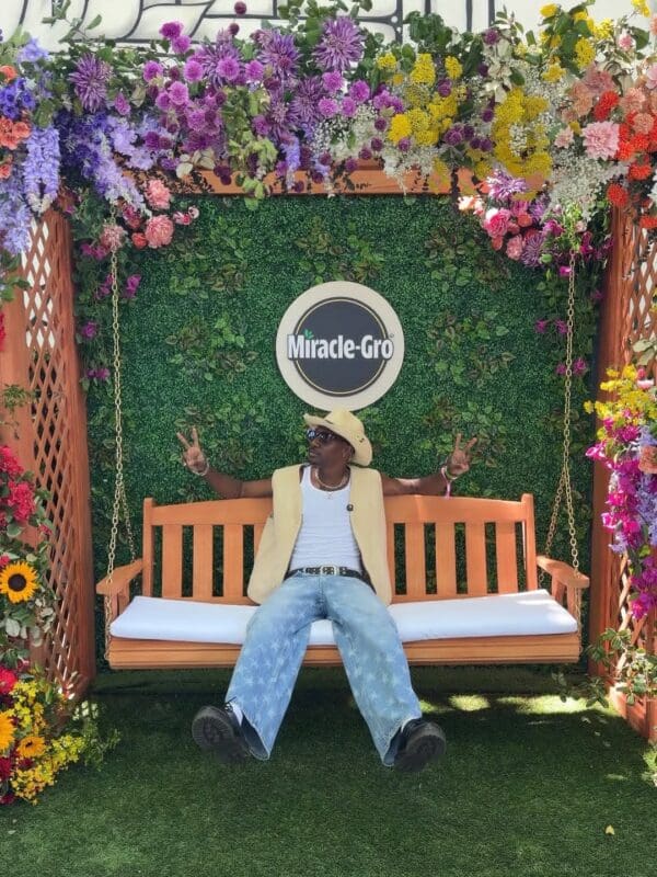 man sitting on swing with Miracle-Gro sign in background